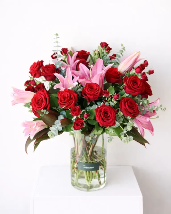Flamingo Rosé arrangement with red roses & pink lilies in a clear vase